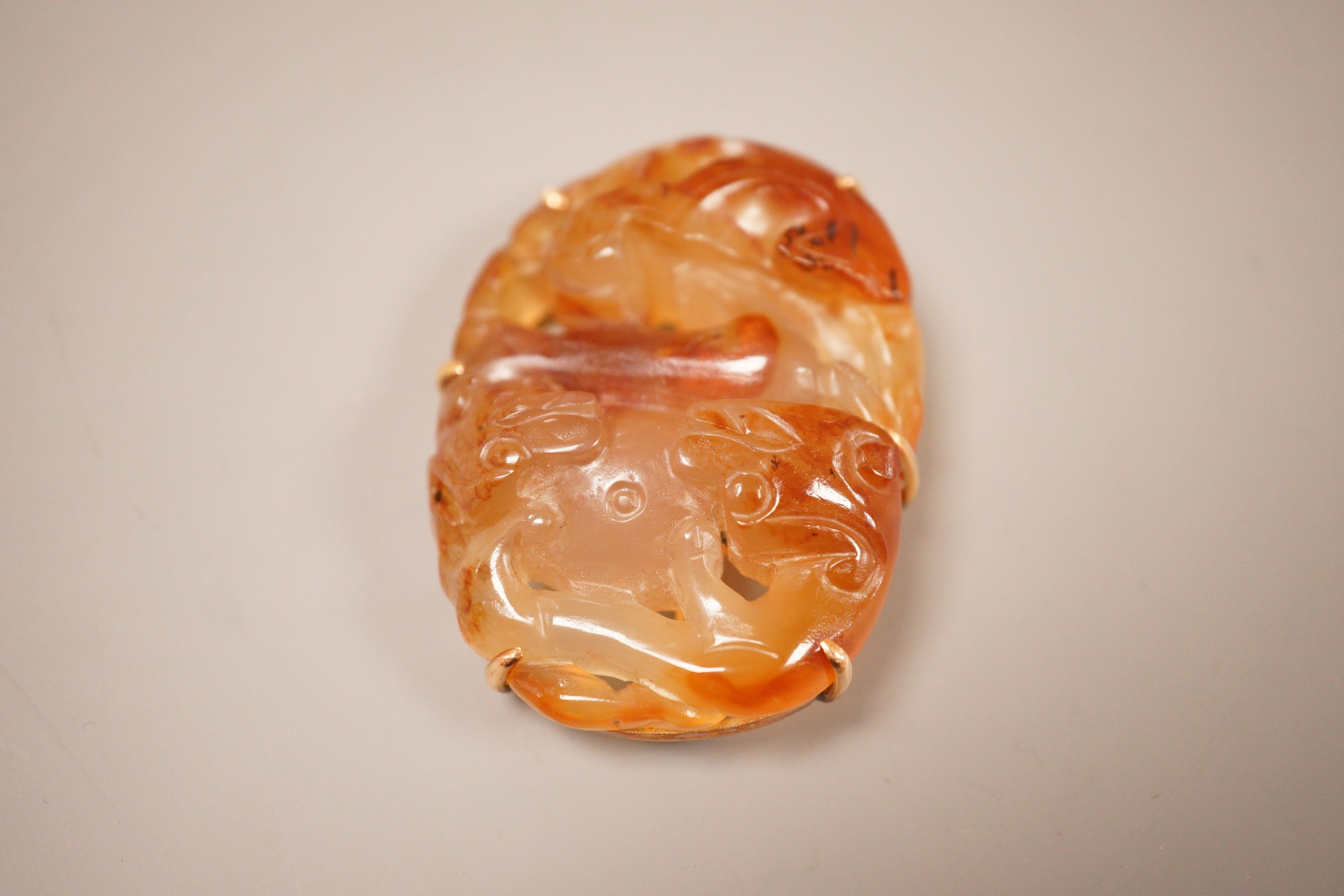 A Chinese carved agate plaque, Qing dynasty, later mounted as a brooch, 5.5cm long